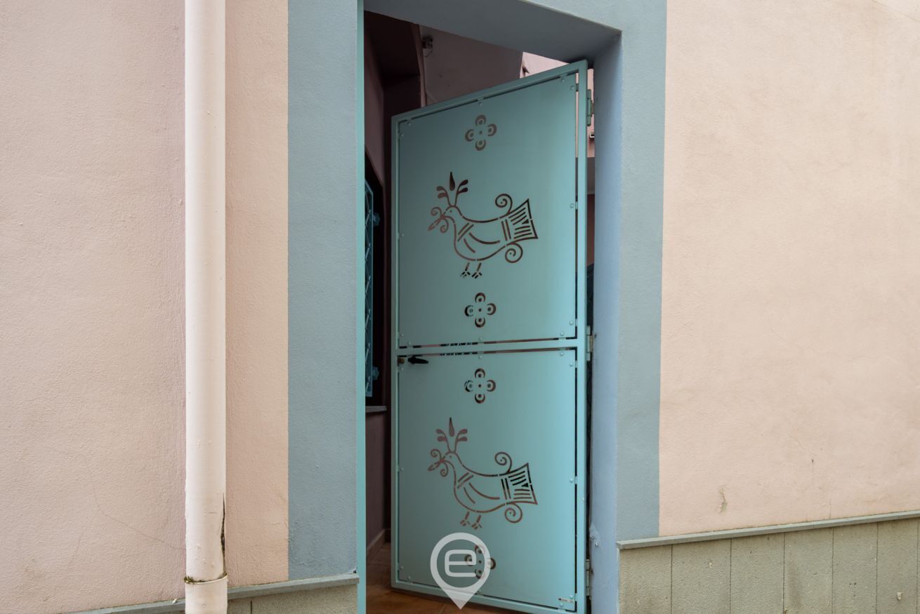 Una puerta doble color turquesa con detalles decorativos de aves.