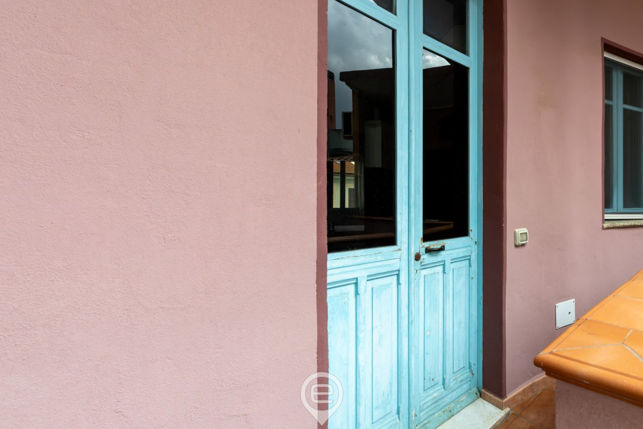 Una pared rosa con una puerta azul y una ventana.