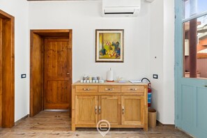 A wooden cabinet with drawers, a framed painting above it, and a tiled floor.