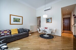 A modern living room with a leather sofa, a dining table with white chairs, and a framed picture on the wall. - YiD Servi suite apt A (Firenze)