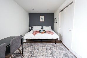 A bedroom with a bed, a desk, and a chair.