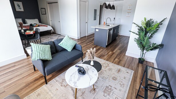 A modern living room with a sofa, coffee table, and a dining area with chairs.