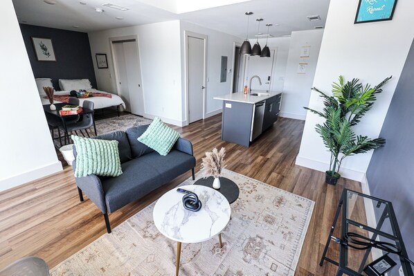 A modern living room with a sofa, coffee table, and a dining area with chairs.