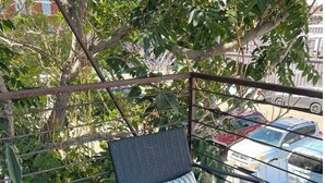 A balcony with a wicker chair and a lantern, surrounded by greenery and parked cars. - Charming 1-bedroom apartment with WiFi, AC in wonderful Denver (Denver)
