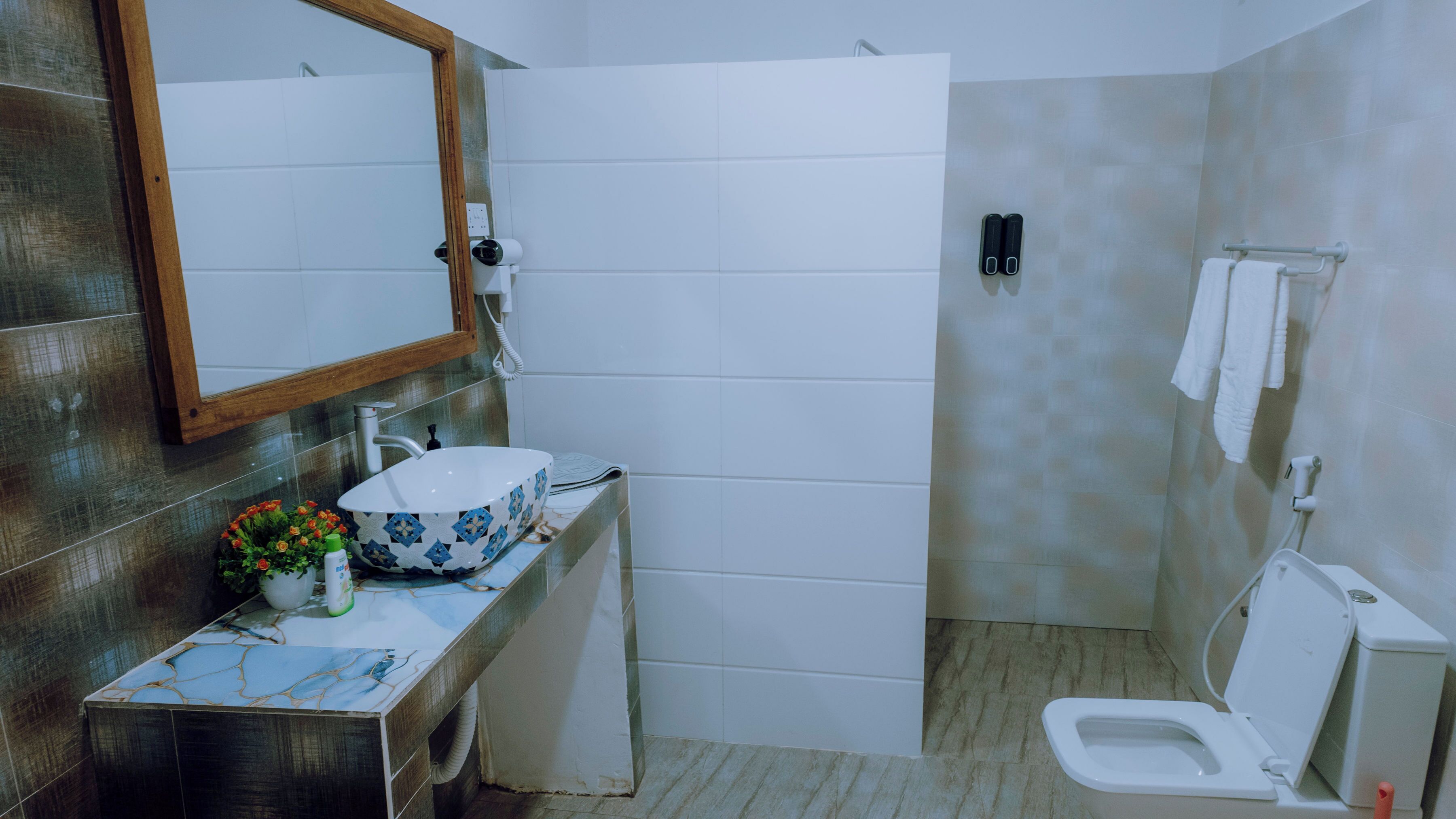 A bathroom with a white sink, a mirror, a shower, and a toilet.