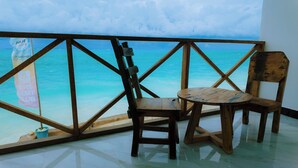 Une chaise et une table en bois, près d’une fenêtre donnant sur l’océan.