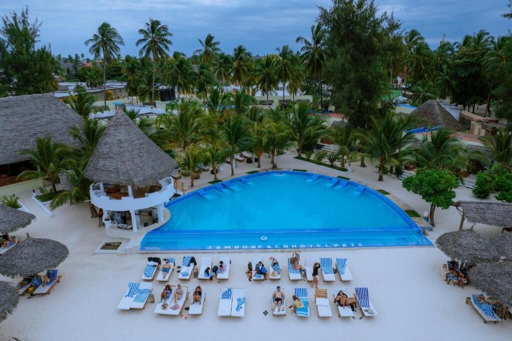 A resort pool with lounge chairs and palm trees.