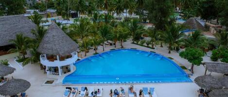 A resort pool with lounge chairs and palm trees.