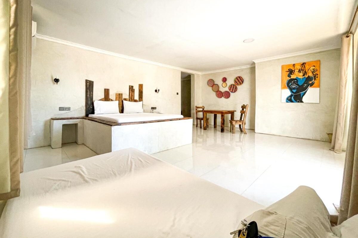 A hotel room with a bed, a desk, a chair, and a dining table.