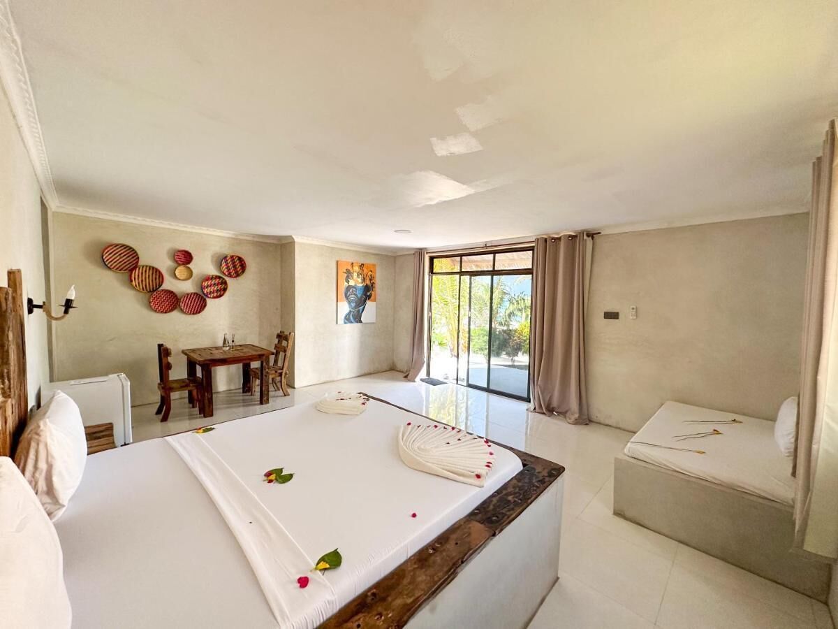 Une chambre d’hôtel avec un lit, une petite table, une chaise, une fenêtre avec des rideaux et un tableau au mur.