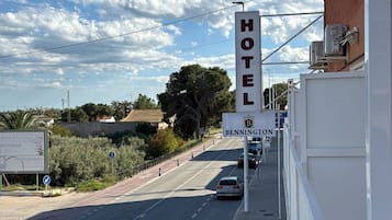 Letrero de hotel con una vista despejada de la carretera y un coche estacionado al lado.