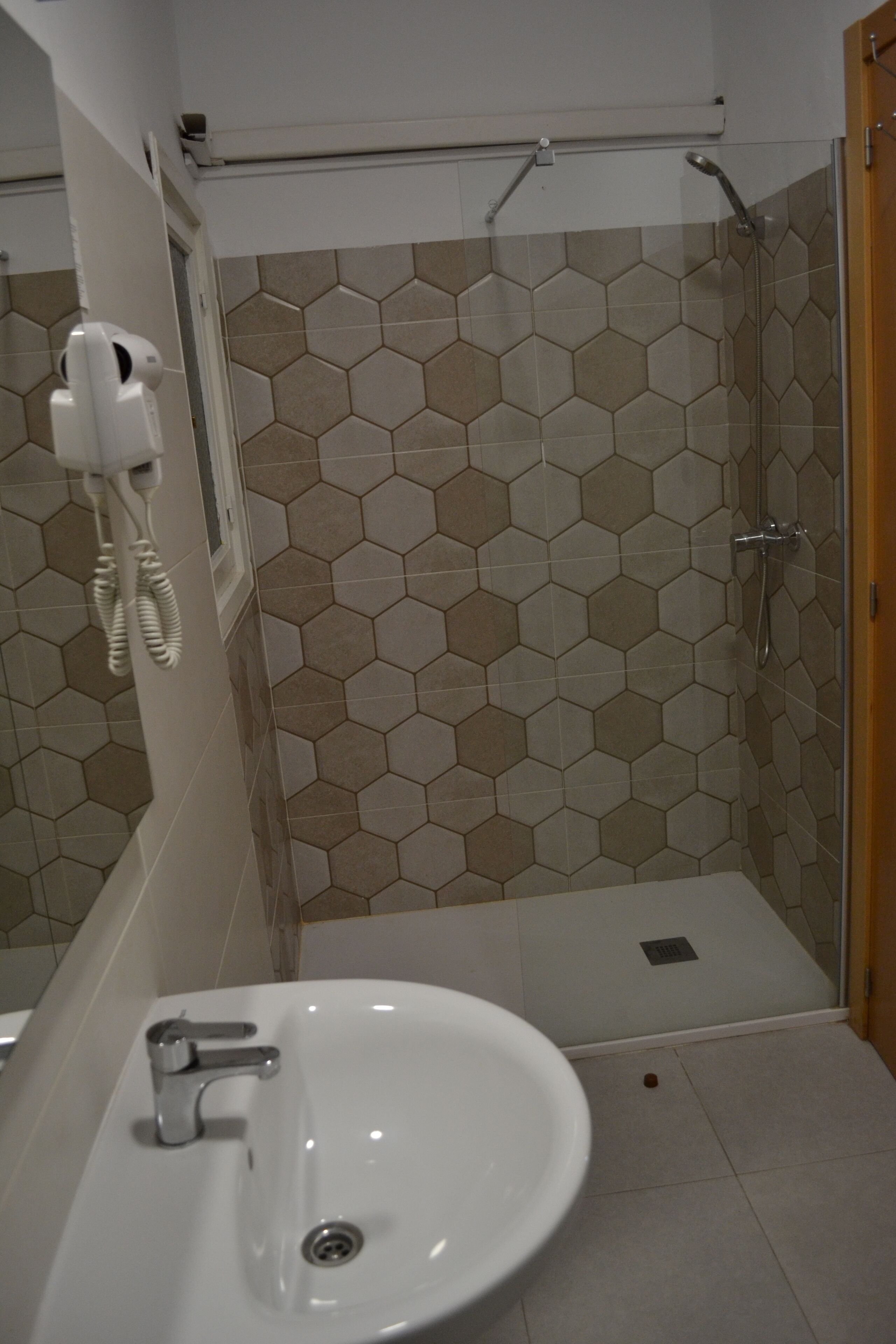 Een badkamer met een wastafel, douche en handdoekhouder.