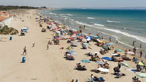 A beach with numerous umbrellas and people. - BENNINGTON (Elche)