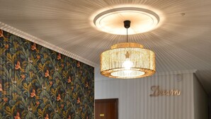 A hallway with a patterned wallpaper, a wooden door, and a hanging light fixture. - BENNINGTON (Elche)