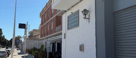 Un hotel llamado 'BENNINGTON' con fachada blanca, un balcón y una persiana cerrada a la derecha.