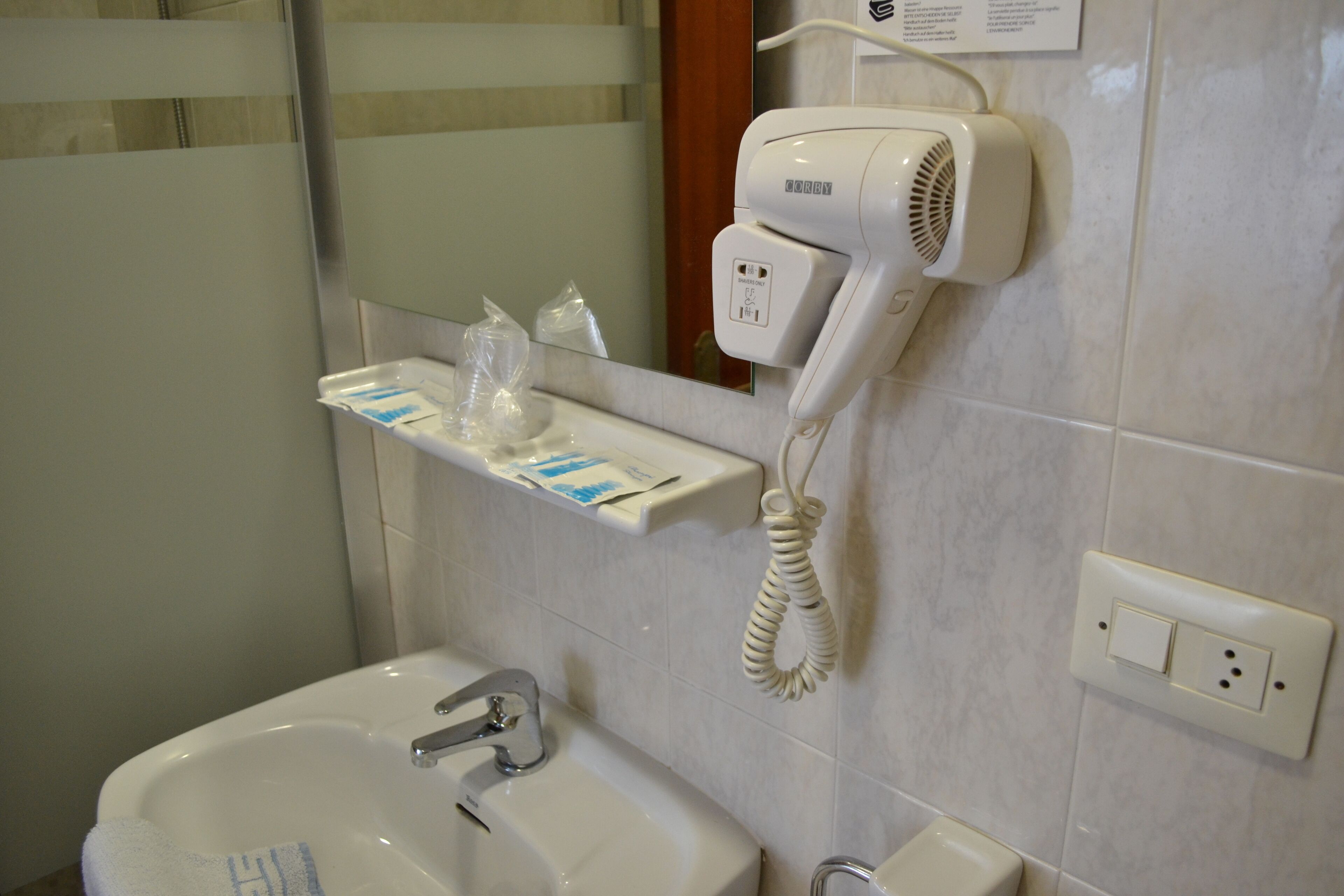 A bathroom with a sink, a hairdryer, and a mirror.