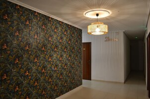 A hallway with a patterned wallpaper, a chandelier, and a door labeled "Dream."