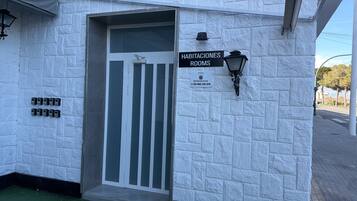 L’entrée d’un hôtel, avec une enseigne indiquant « HABITACIONES ROOMS » et un numéro de téléphone.