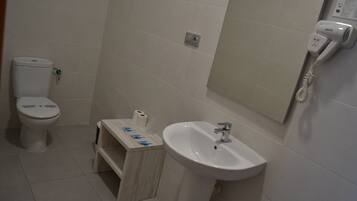 A bathroom with a toilet, a sink, and a hairdryer mounted on the wall.