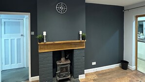 Una sala de estar moderna con chimenea, un reloj en la pared y una puerta que da a otra habitación.