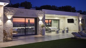 Un espace de vie extérieur moderne, agrémenté d’un mur en pierre, d’une porte coulissante en verre et d’un coin salon.