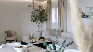 Un salon moderne avec un canapé blanc, une table basse et une plante.