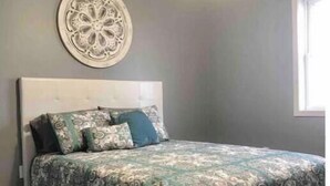 Una camera da letto con un letto, una ventola a soffitto e un elemento decorativo a parete.