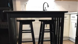 A kitchen with a black metal table and two stools.