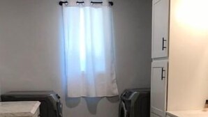 A compact laundry room with a washing machine, dryer, and stacked cabinets. - Easy Street Apartment (Van Buren)