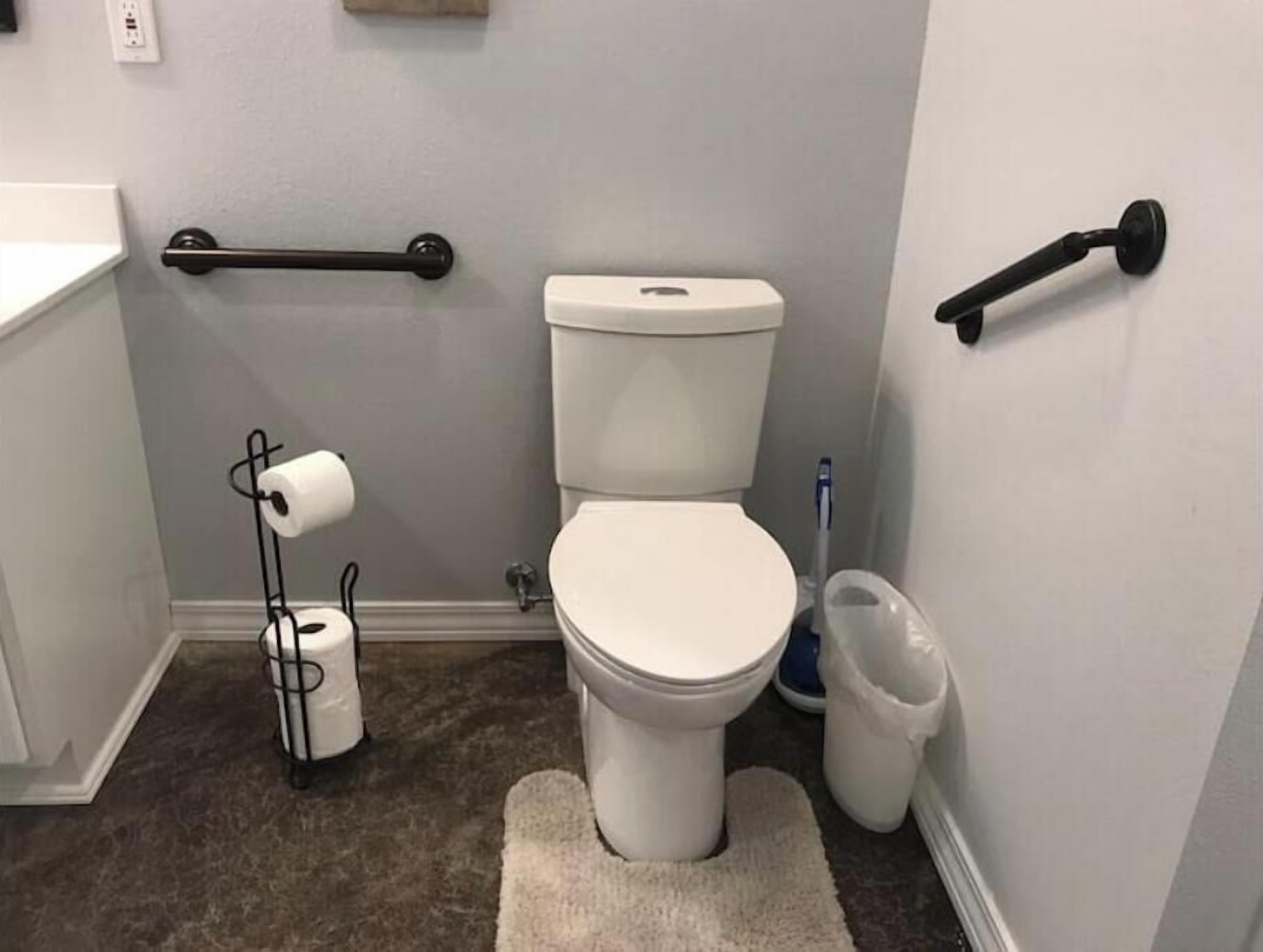 Ein kleines Badezimmer mit Toilette, Handtuchhalter, Toilettenpapierhalter und Mülleimer.