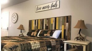 A bedroom with a bed, two bedside lamps, a wall clock, and a motivational quote. - Easy Street Apartment (Van Buren)