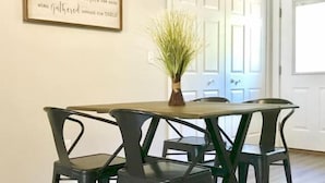 A dining area with a table and four chairs, a vase with greenery, and a framed quote on the wall. - River Ridge Retreat (Van Buren)