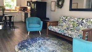 A modern living room with a blue armchair, patterned sofa, and a round rug. - River Ridge Retreat (Van Buren)