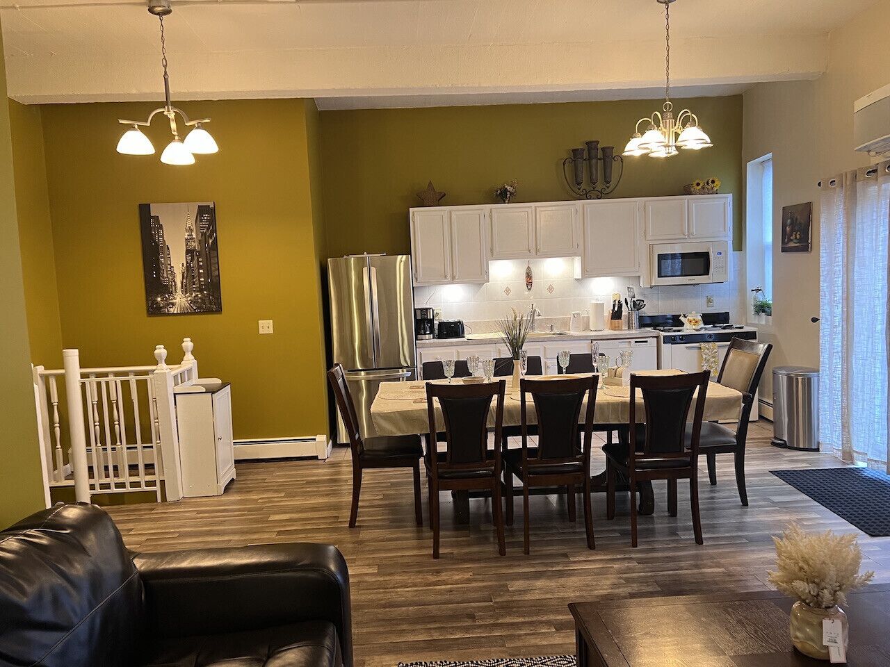 A modern kitchen with white cabinets, a stainless steel refrigerator, and a microwave.