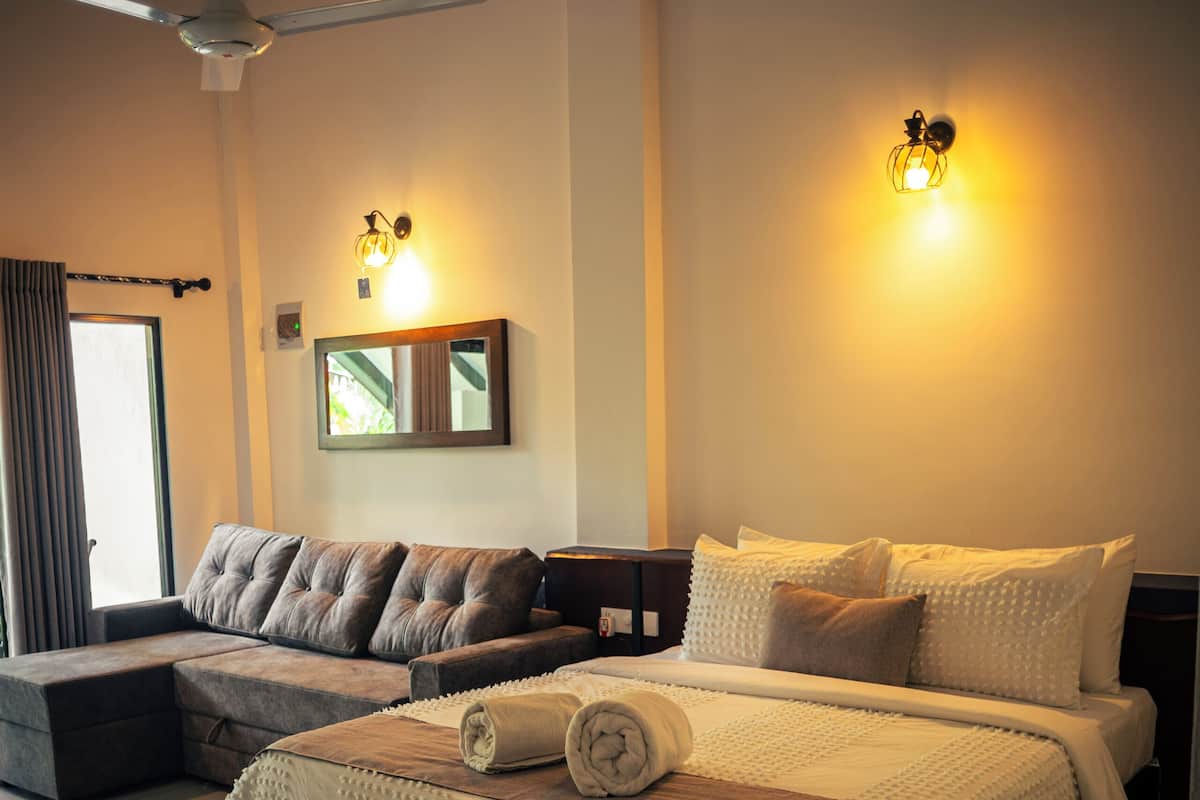 Ein modernes Schlafzimmer mit einem großen Bett, einer Couch, einem Deckenventilator und Wandleuchten.