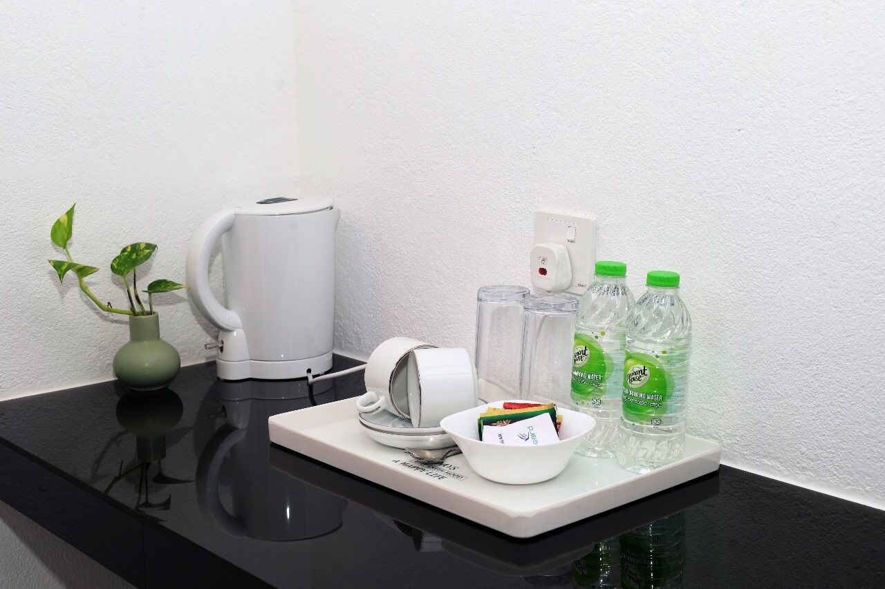 A small kitchenette with a coffee maker, a bowl of snacks, and two bottles of water on a tray.