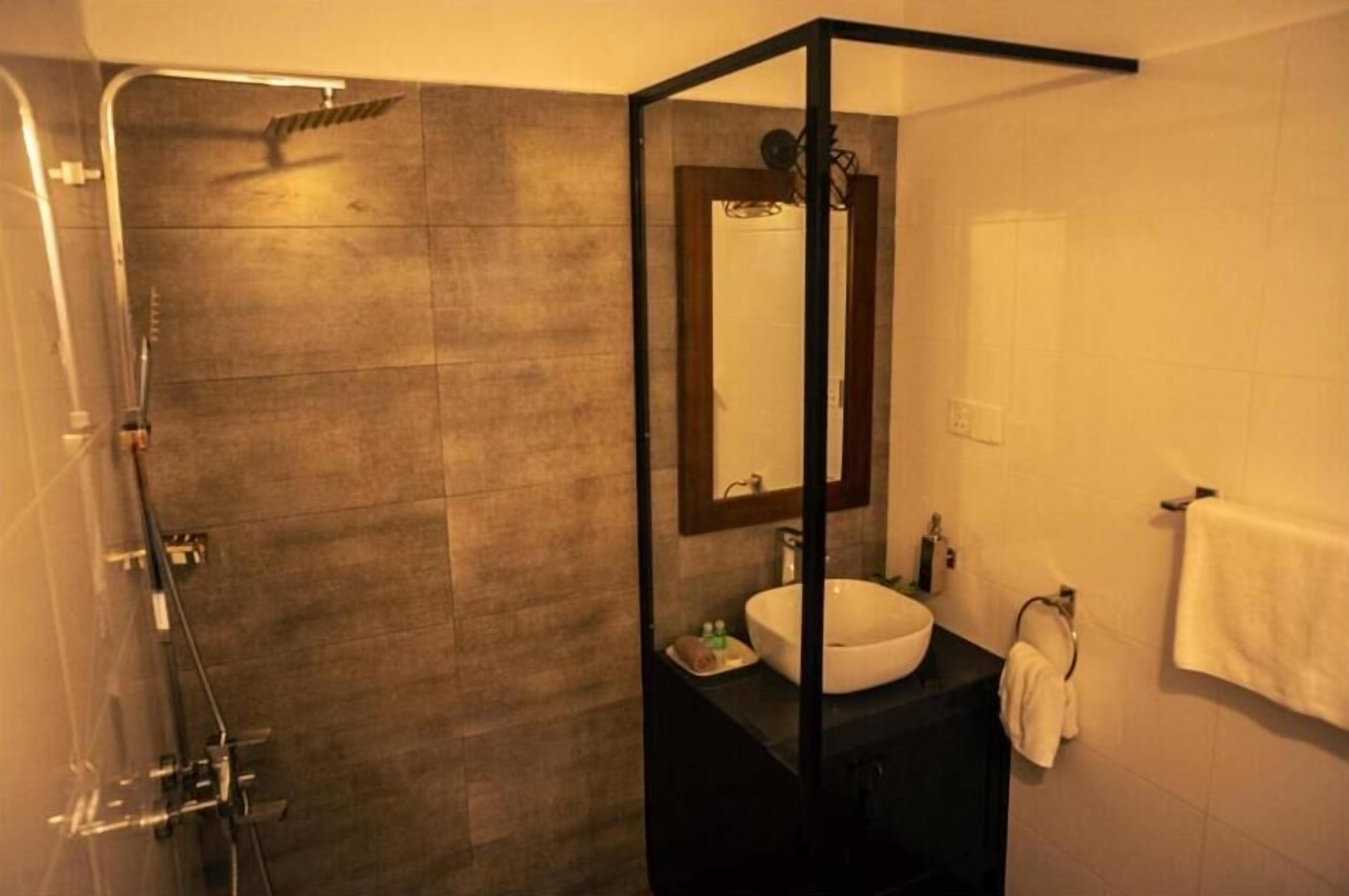 A modern bathroom with a glass-enclosed shower, a large mirror, and a white sink.