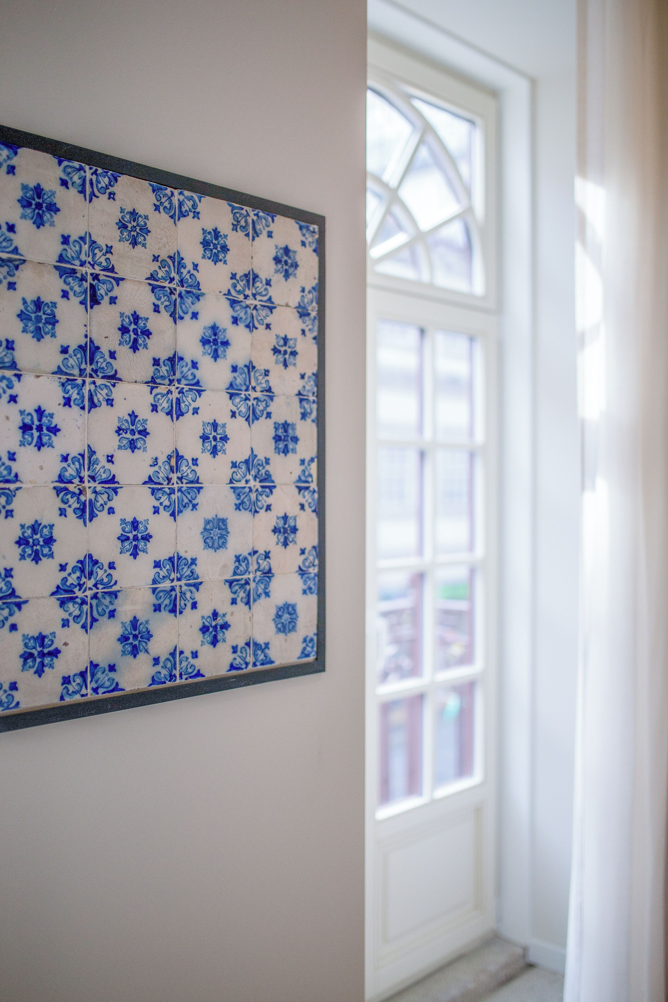A wall with blue floral tiles and a white door with glass panels.