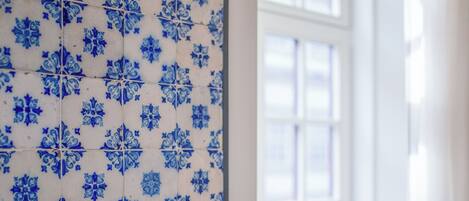 A wall with blue floral tiles and a white door with glass panels.