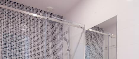 A modern bathroom with a glass shower enclosure, a white sink, and a toilet.