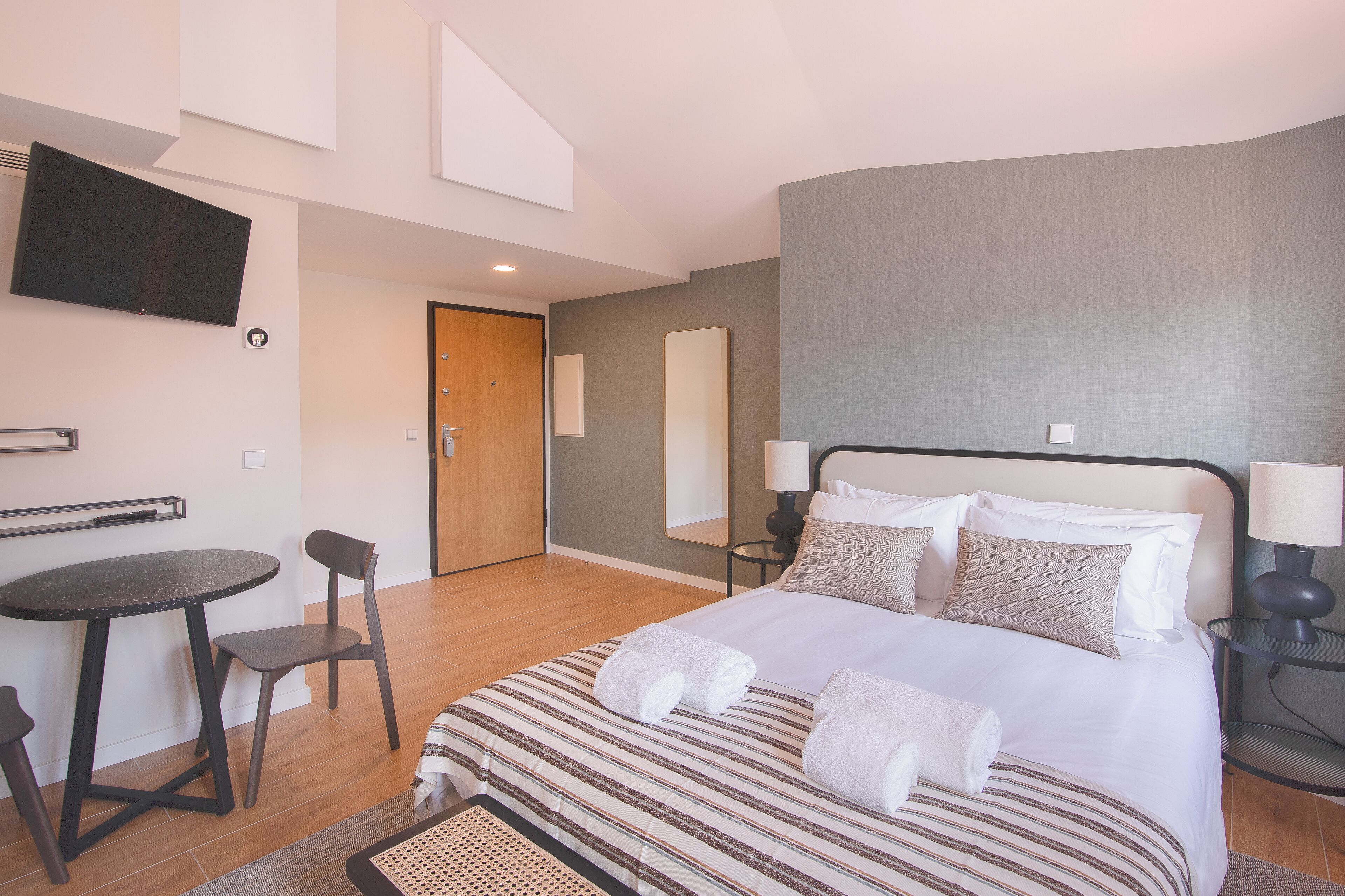 Ett modernt hotellrum med en säng, ett litet bord och en stol.