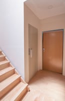 A staircase leading to a wooden door with a handle.