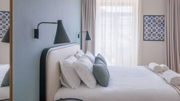 A neatly made bed with white and grey pillows, a bedside lamp, and a framed artwork on the wall.