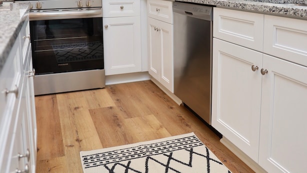 Une cuisine moderne avec des meubles blancs, des appareils en acier inoxydable et un plancher en bois.