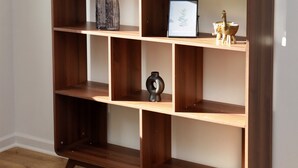Une bibliothèque en bois avec plusieurs étagères, un tableau encadré et une petite sculpture.