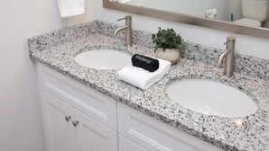 Une salle de bain avec deux lavabos, un grand miroir et un porte-serviettes.