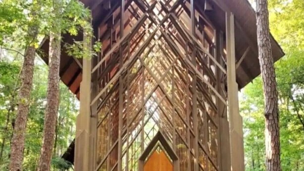 Une structure en bois surmontée d’un toit à motifs losangés, entourée d’arbres.