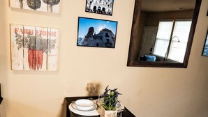 Un coin repas avec une table en bois foncé, dressée pour quatre personnes, des chaises blanches et un miroir au-dessus.