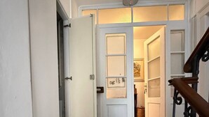 A hallway with a wooden staircase on the right, a white door at the end, and a rug on the floor. - Apartment in Vallemaggia Cevio (Cevio)