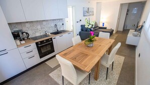 A modern kitchen with white cabinets, a wooden dining table, and a vase of flowers. - Holiday apartment with air conditioning (Poreč)